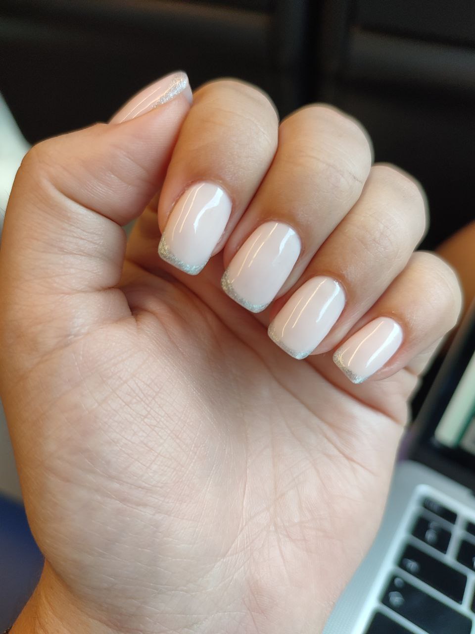 Hand met korte, vierkante melkwitte nagels